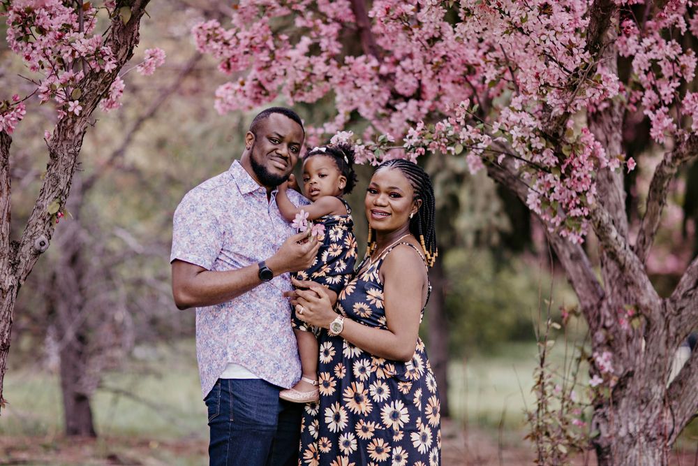 A family shares a joyful moment together under blooming pink cherry blossom trees in a spring garden.