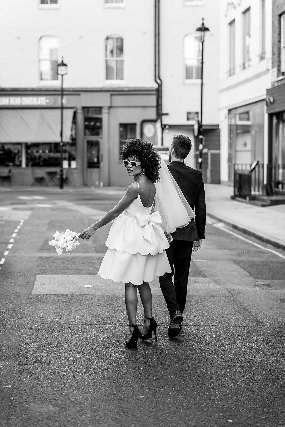 Black and white street photography of couple walking away holding sparklers.
