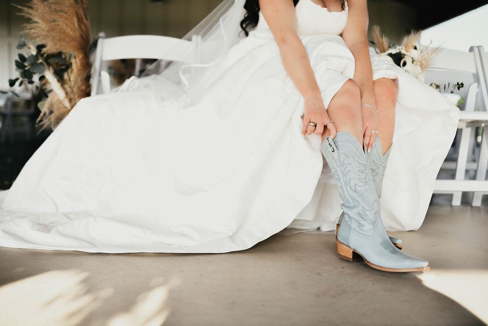 the bride pulls up her baby blue cowgirl boots for her wedding reception
