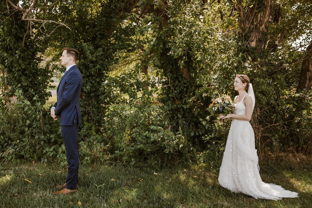 Groom holding back tears during a first look with his bride, surrounded by nature and Kansas City sunshine.
