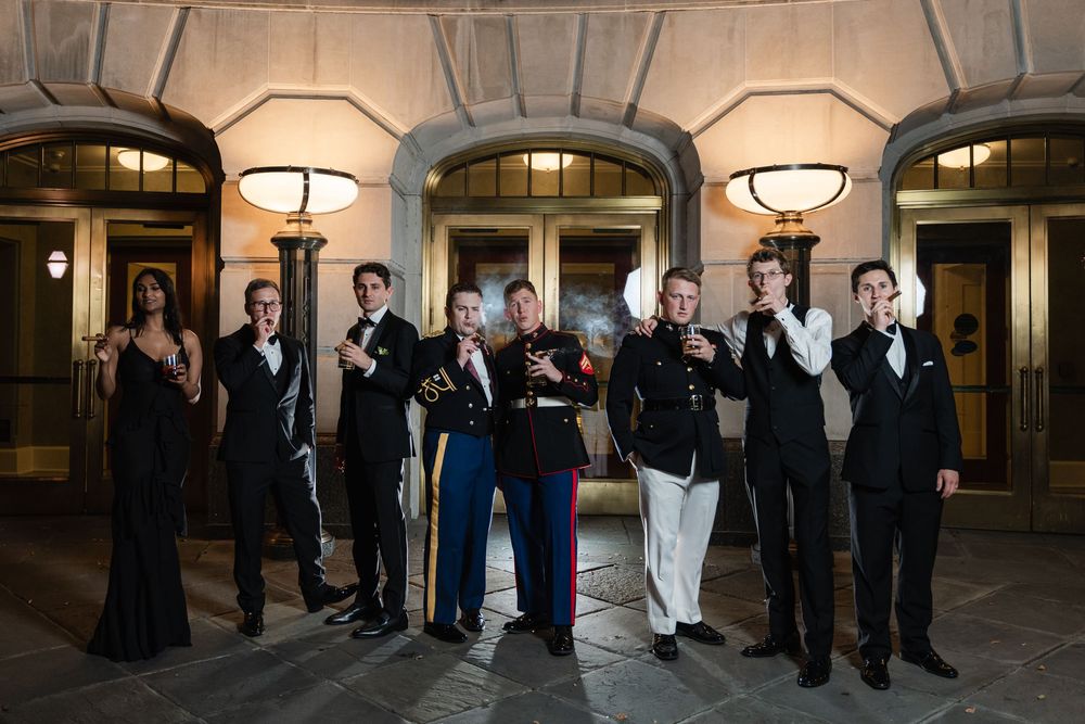 Group of formal-dressed attendees standing in elegant venue with illuminated archways for an evening event.