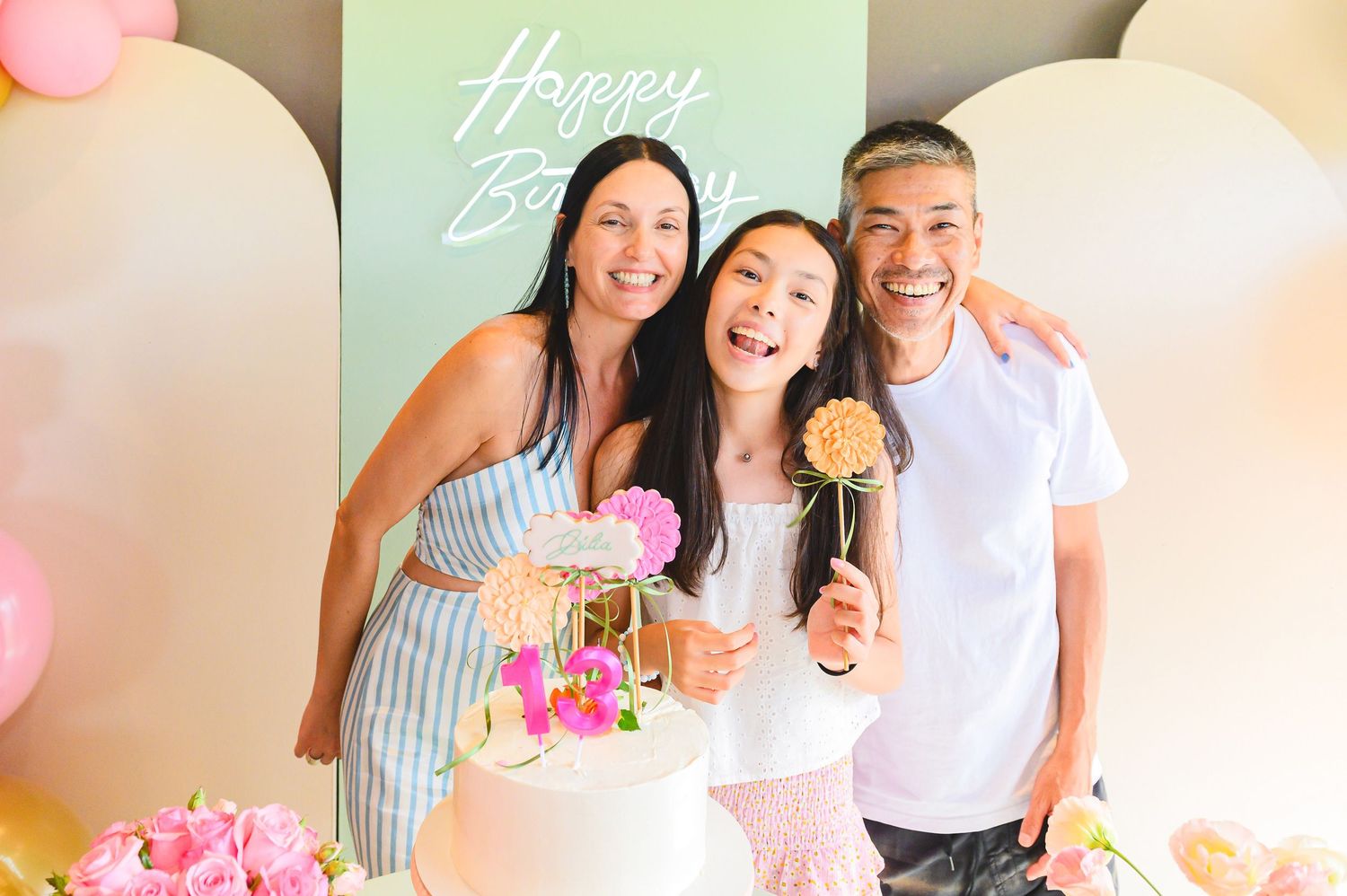 Birthday celebration with pink and cream balloons, cake pops and mint green letters spelling Happy Birthday in the background.
