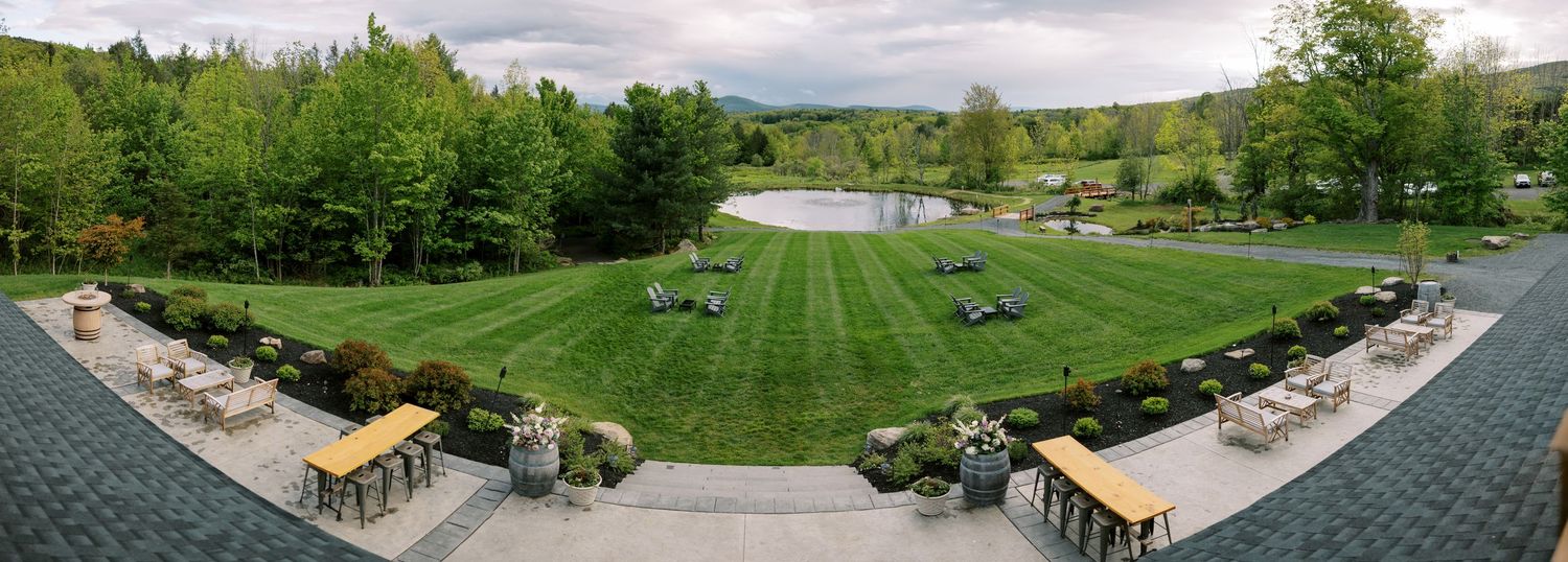 Panoramic view of a well-maintained grass lawn with wooden pergolas and pathways surrounded by lush green trees at Windham Manor.
