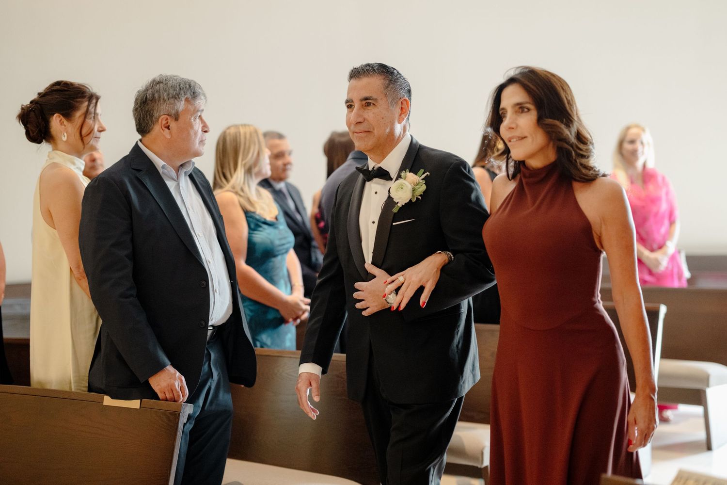A group of well-dressed guests chat before a formal event in an elegant indoor setting.