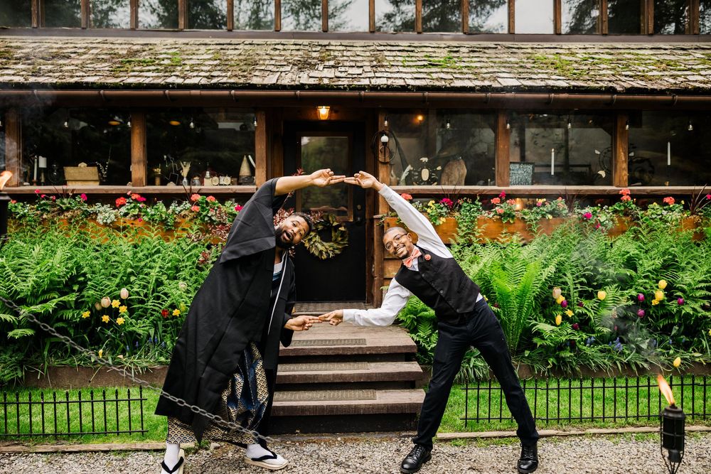 Wedding party members pose playfully in front of rustic lodge building.
