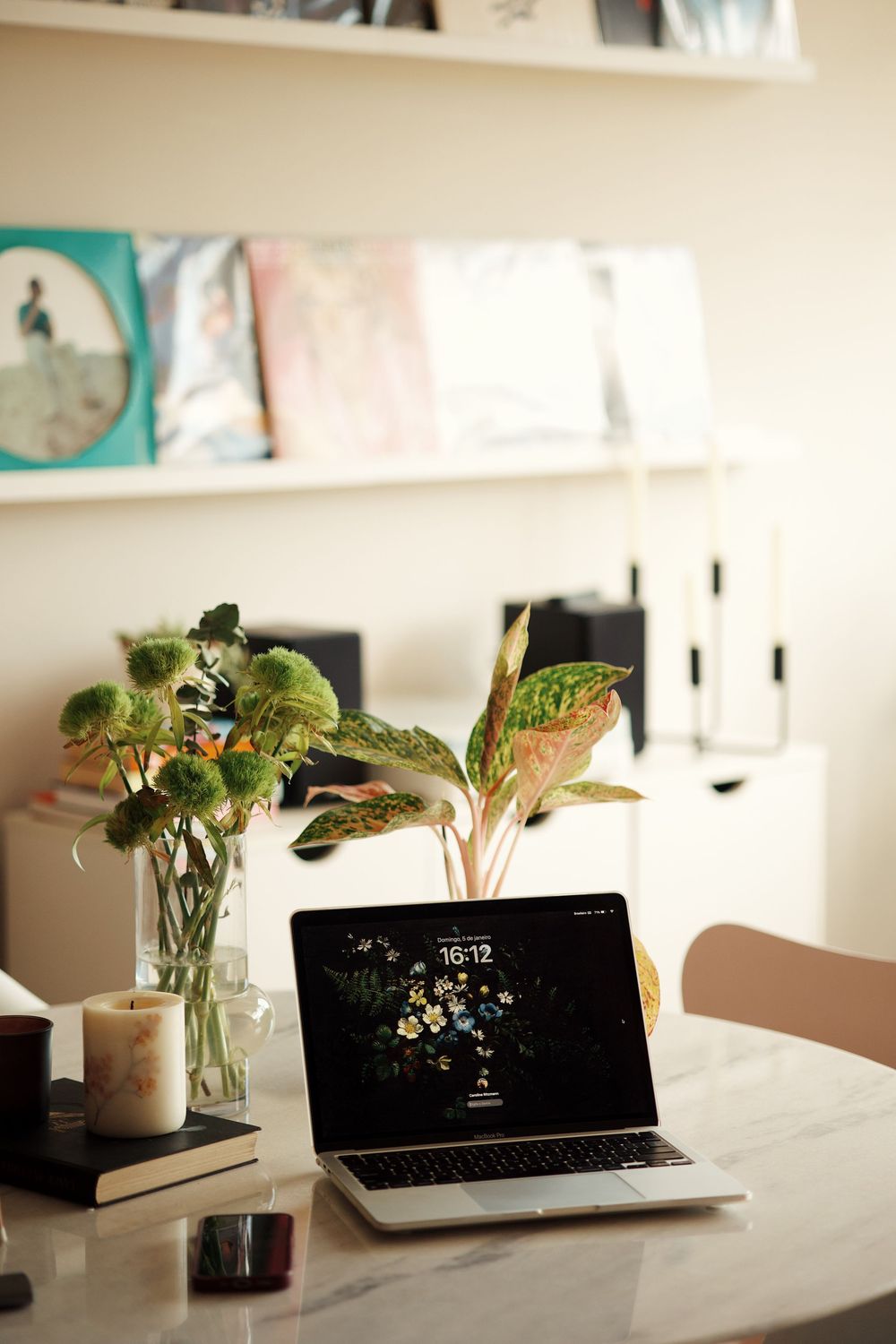 Modern workspace setup with laptop, plants and minimal decor on white desk.