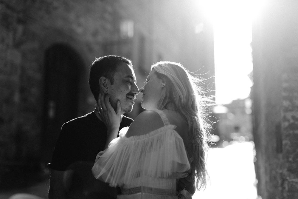 A romantic monochrome moment captured in dramatic lighting with soft backlit glow through an archway.