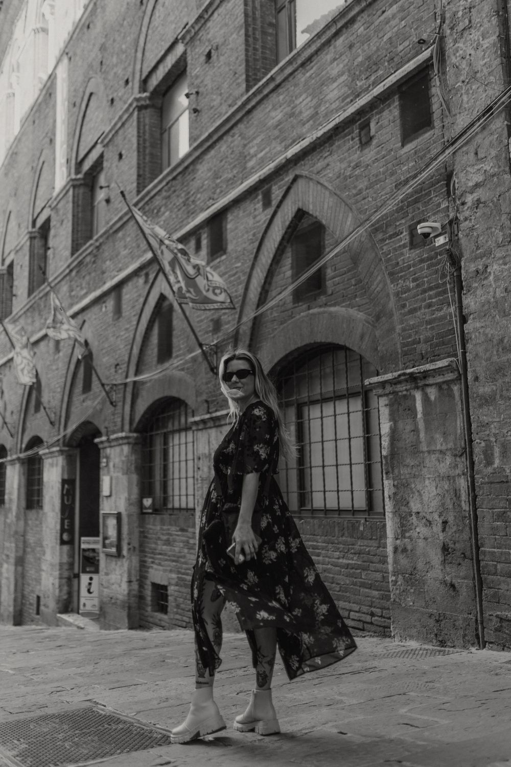 Street fashion portrait in front of rustic Italian architecture with arched windows.