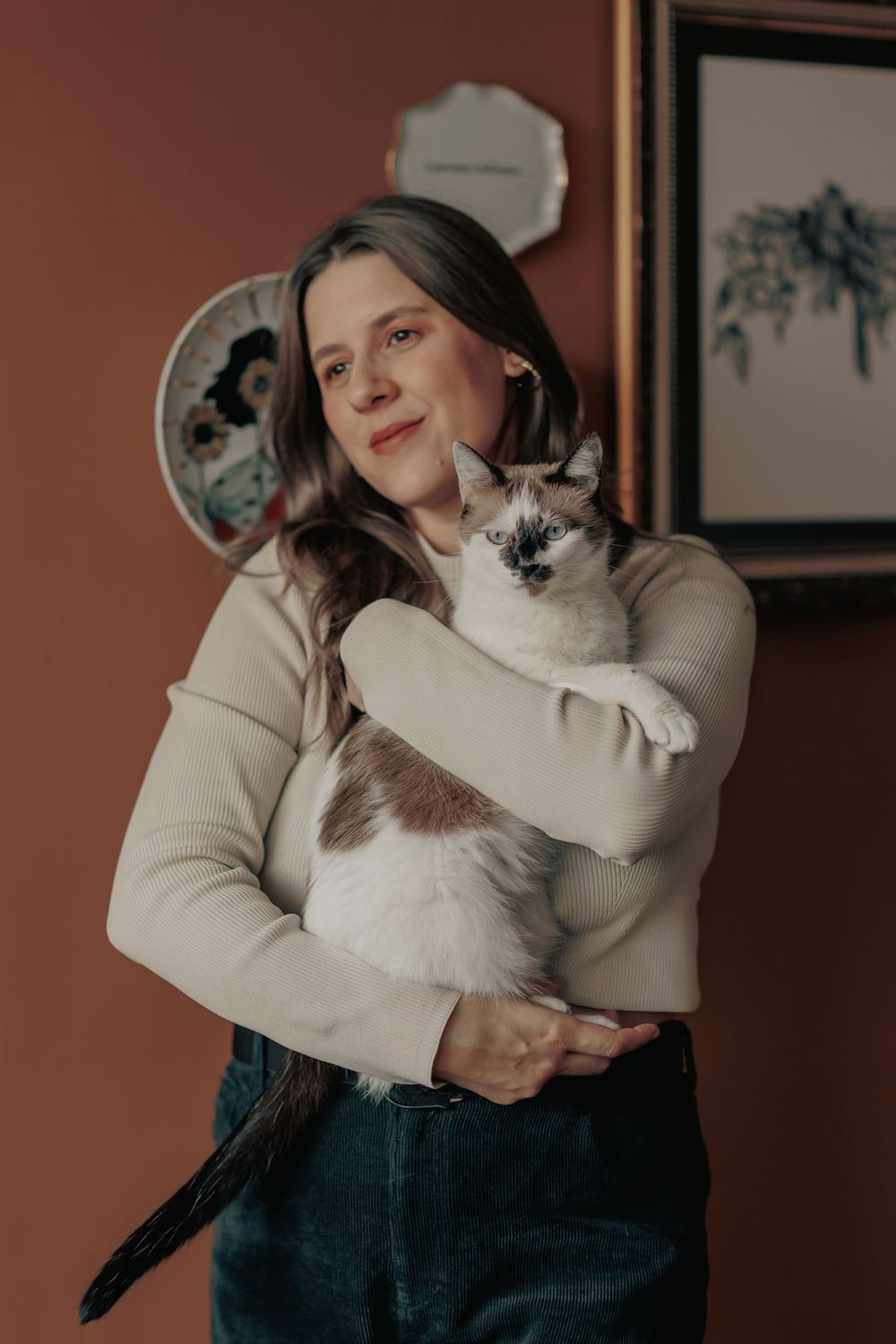 Siamese cat being held lovingly while sitting on a cozy sweater.