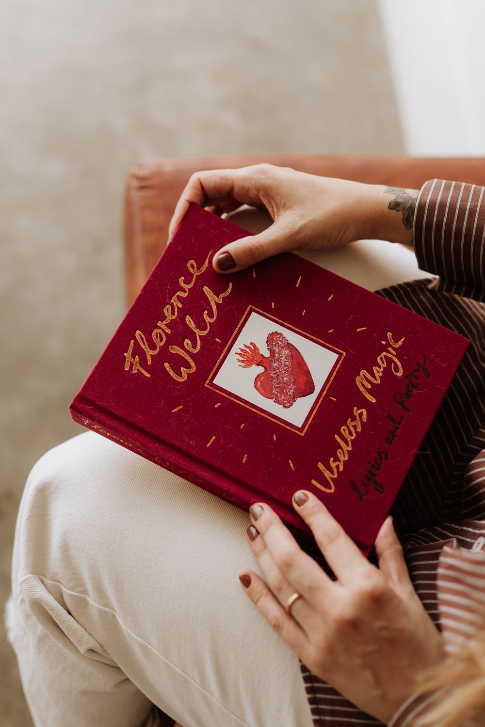 Hands holding a red velvet wedding guestbook with gold lettering and heart embellishment.