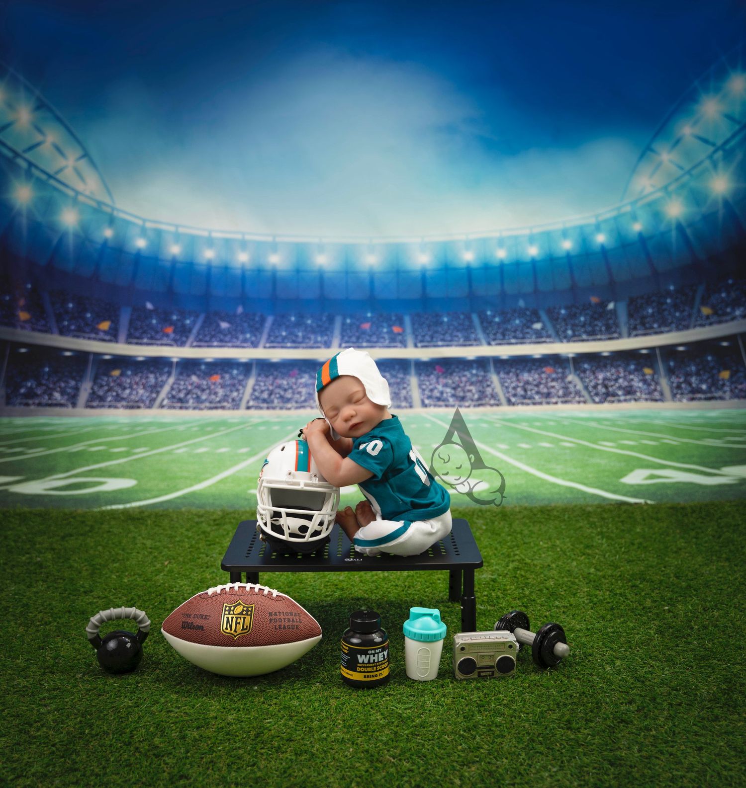Sports-themed newborn photo setup with football equipment in stadium setting.