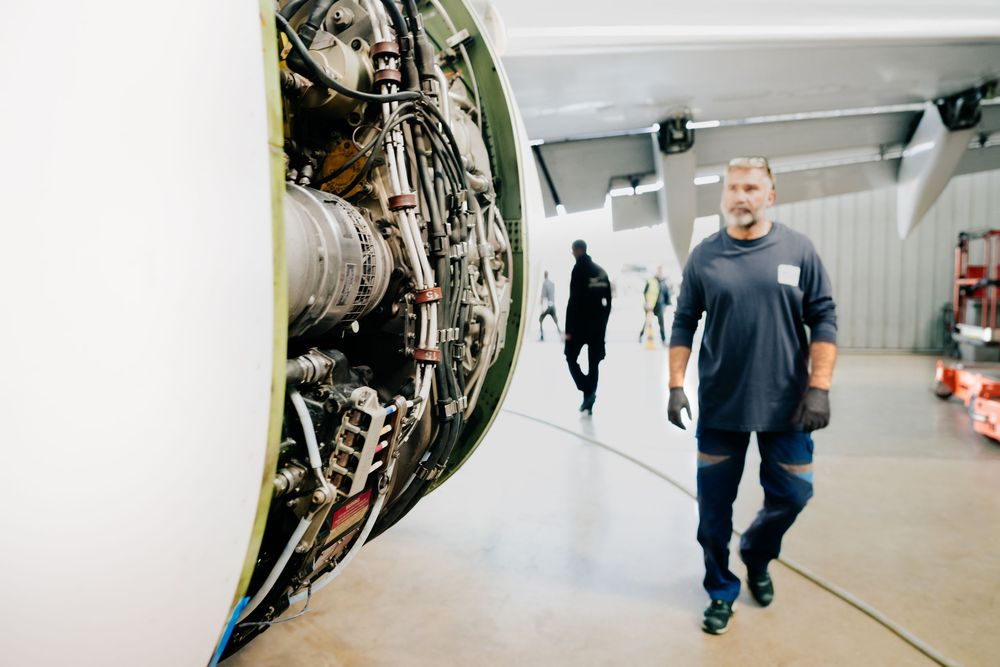 Photographe toulouse. Un moteur à réaction est exposé dans un couloir lumineux tandis que quelqu'un passe devant lui en t-shirt bleu.
