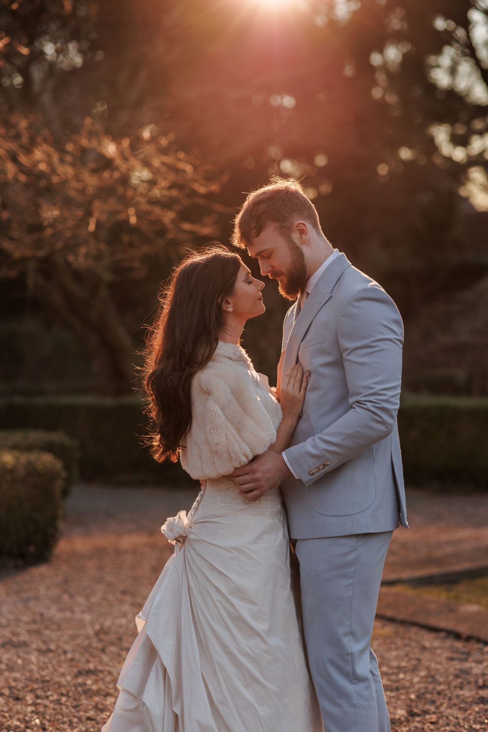 Couple sharing romantic moment at sunset with golden light filtering through trees.