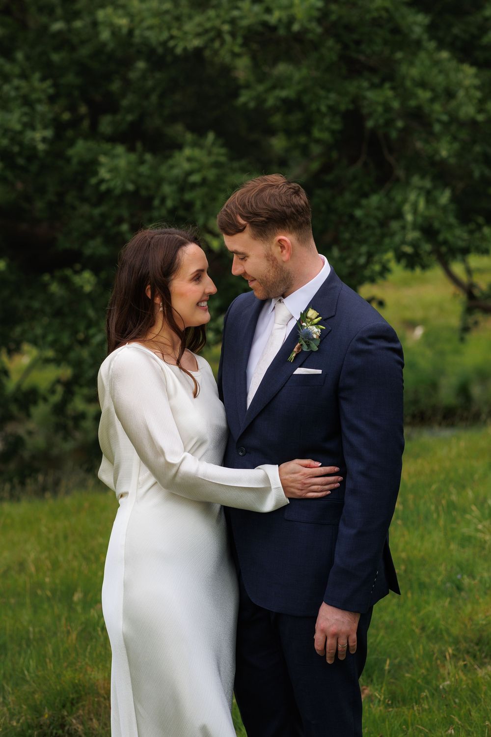 Intimate wedding portrait in a lush green garden setting.