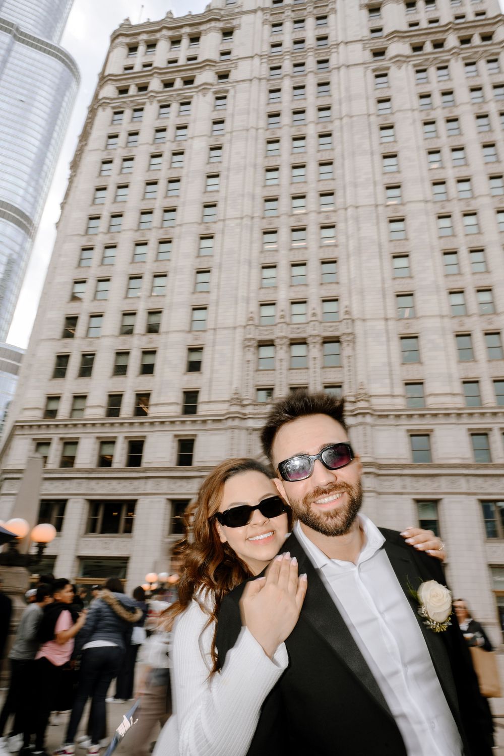 Couple celebrates their wedding day outside a grand historic building in downtown Chicago wearing sunglasses and formal attire.