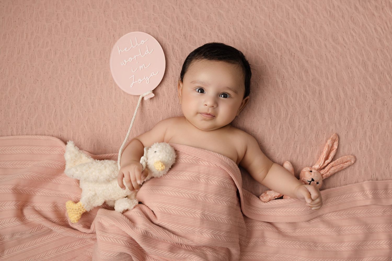 Expectant mother in beige loungewear poses on floor during maternity photoshoot.