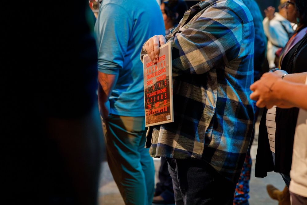 A person holds a protest sign while standing in a crowd wearing blue and plaid clothing.