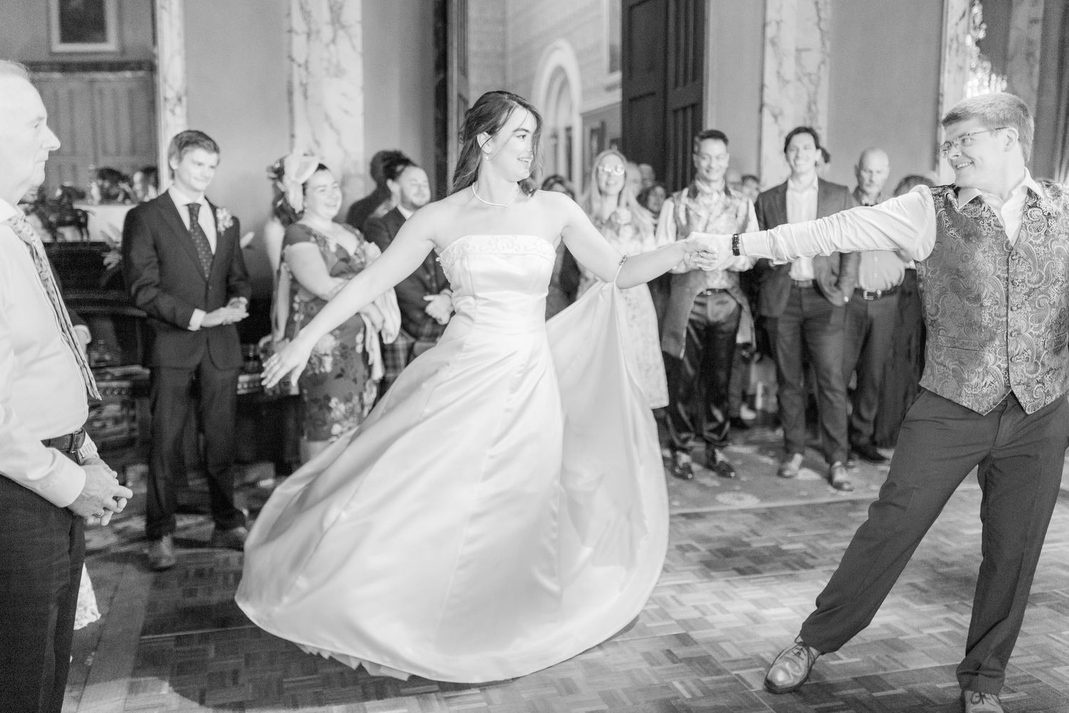 A bride and groom dance together during their first dance at a wedding reception as guests watch at Eastnor Castle by Hayley Elizabeth photo