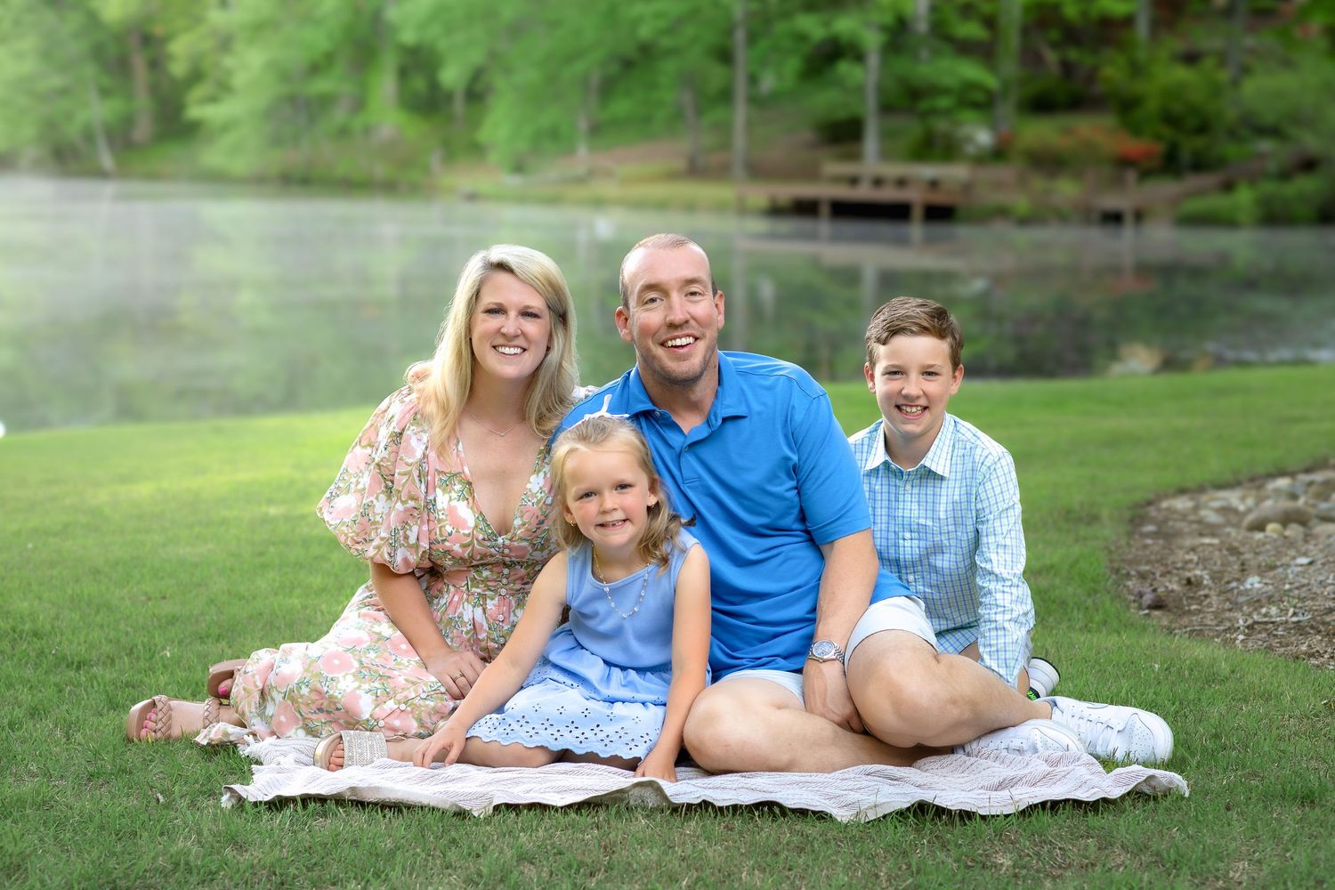 Family of four smile sitting on ground with lake during a family session in Athens, GA - Athens, Watkinsville & Bogart family photographer