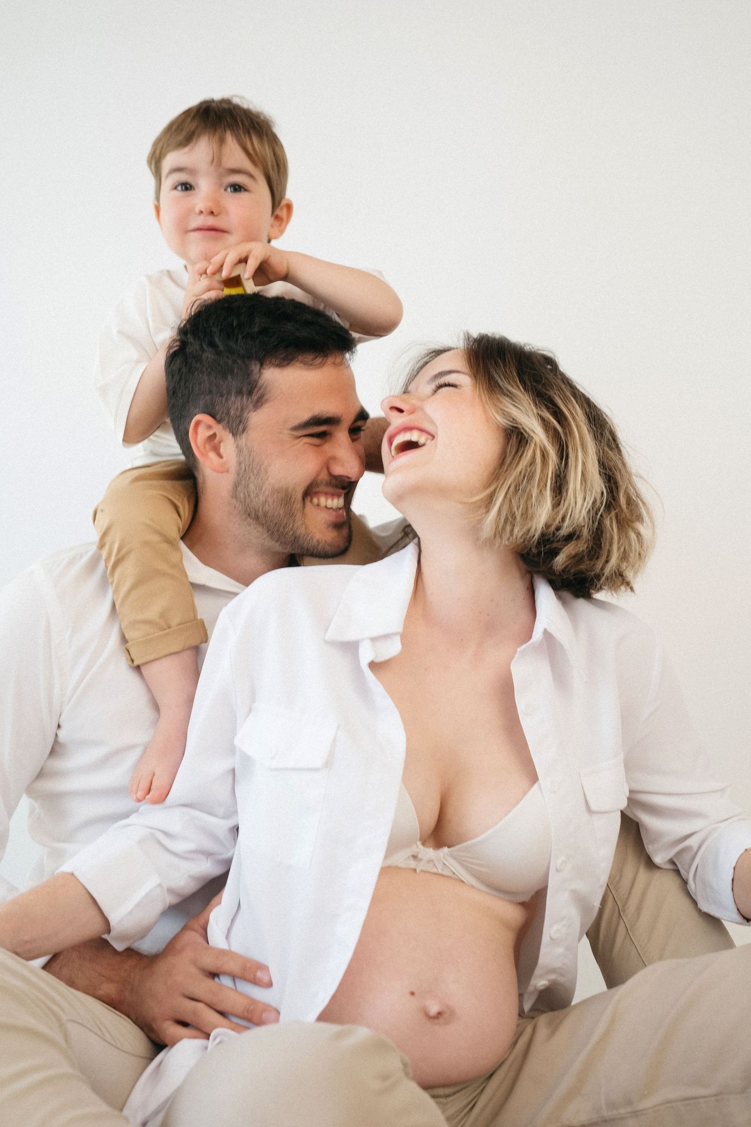 Retrato artístico de maternidad con tela blanca drapeada que enmarca un vientre embarazado.