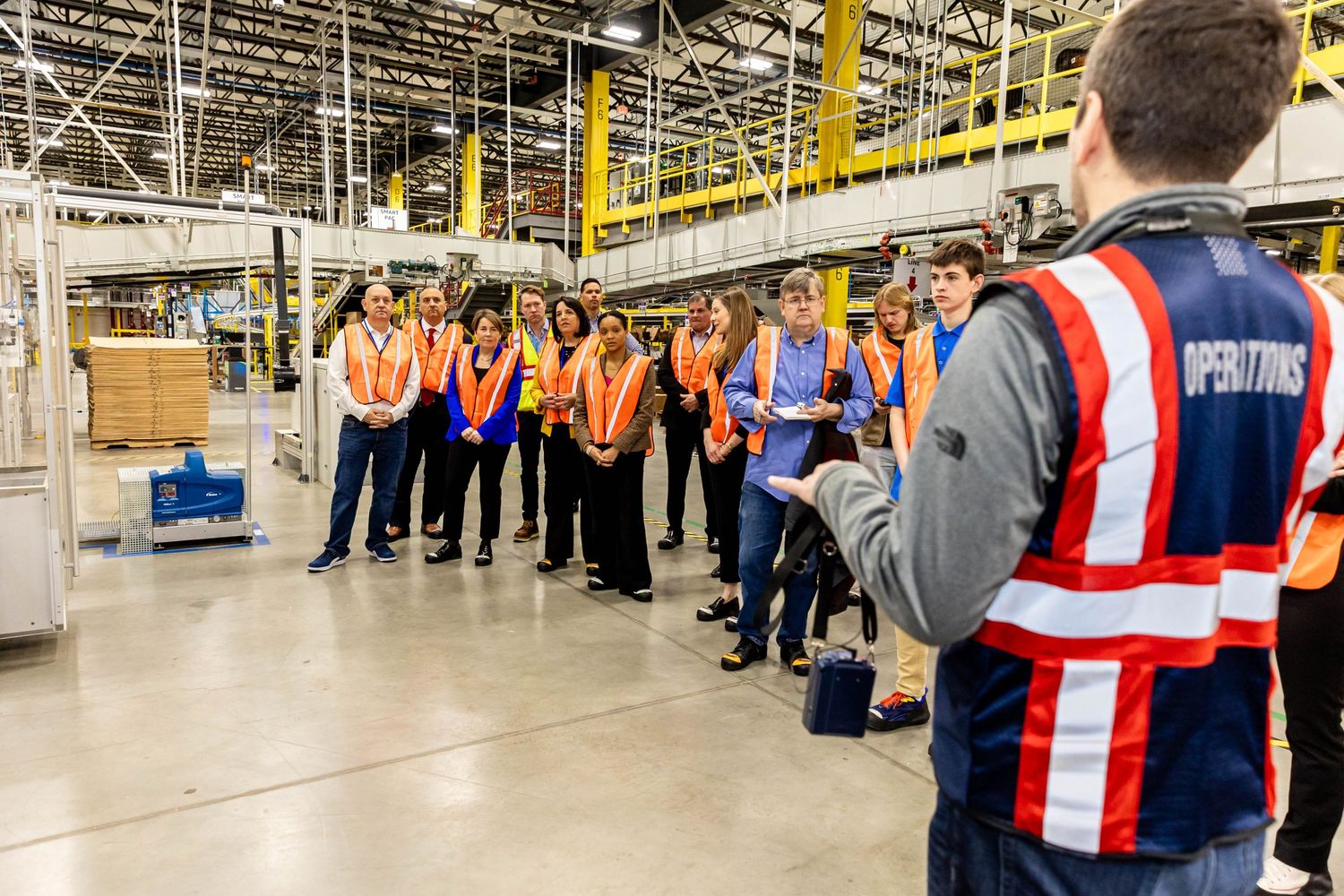 Warehouse workers gather for safety meeting in large distribution center.