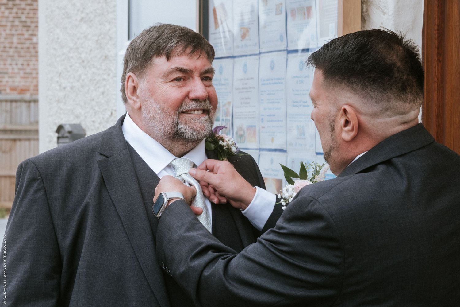 Groom getting his boutonniere pinned to his suit lapel