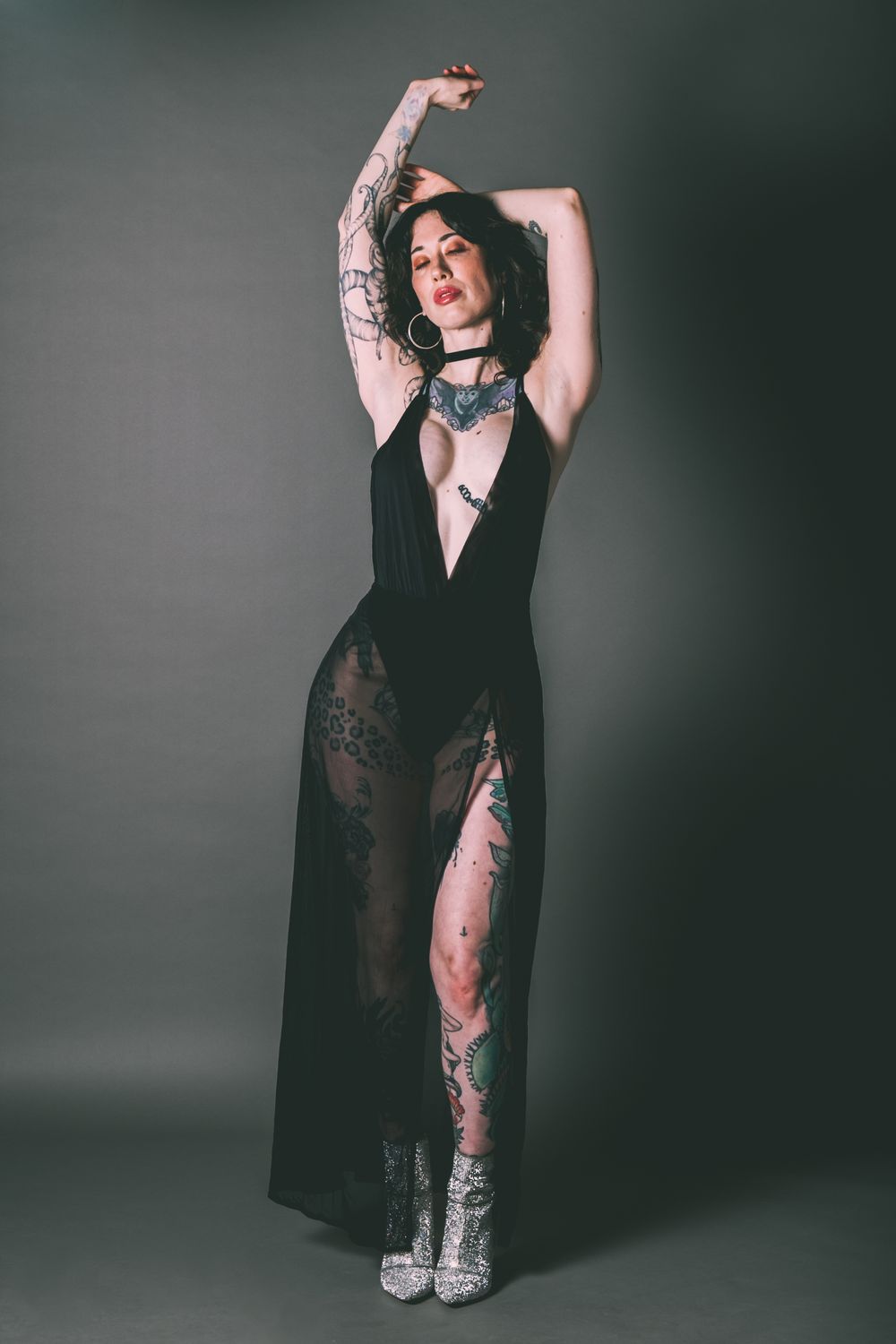 Artistic portrait of a model in black lace dress showing tattoo artwork.