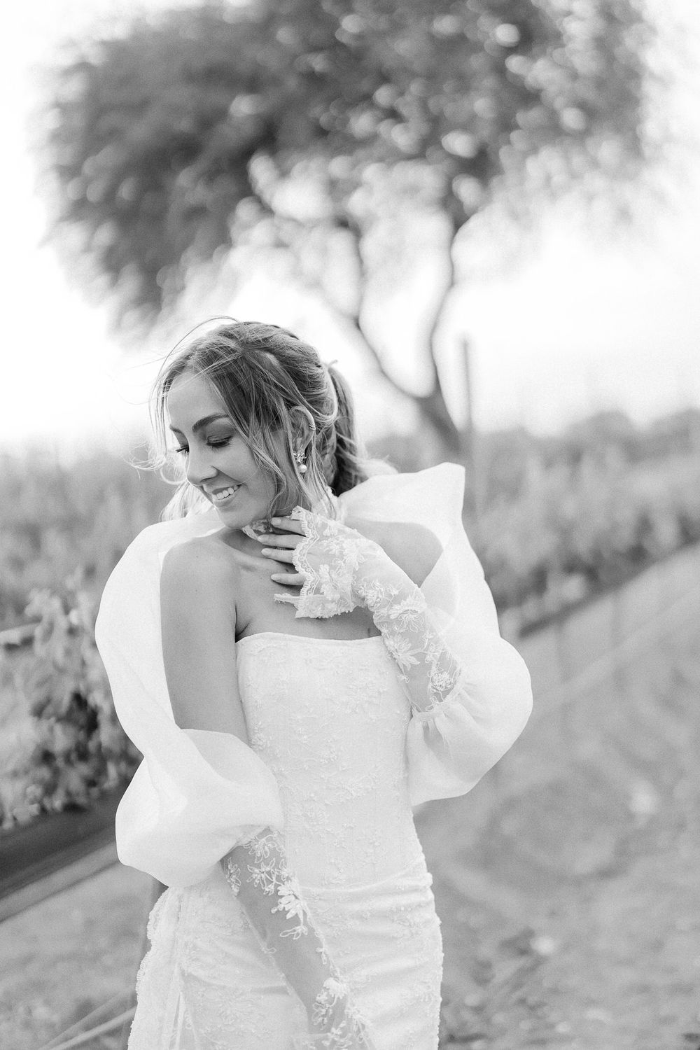 Black and white portrait of bride in strapless gown with dramatic bokeh background.