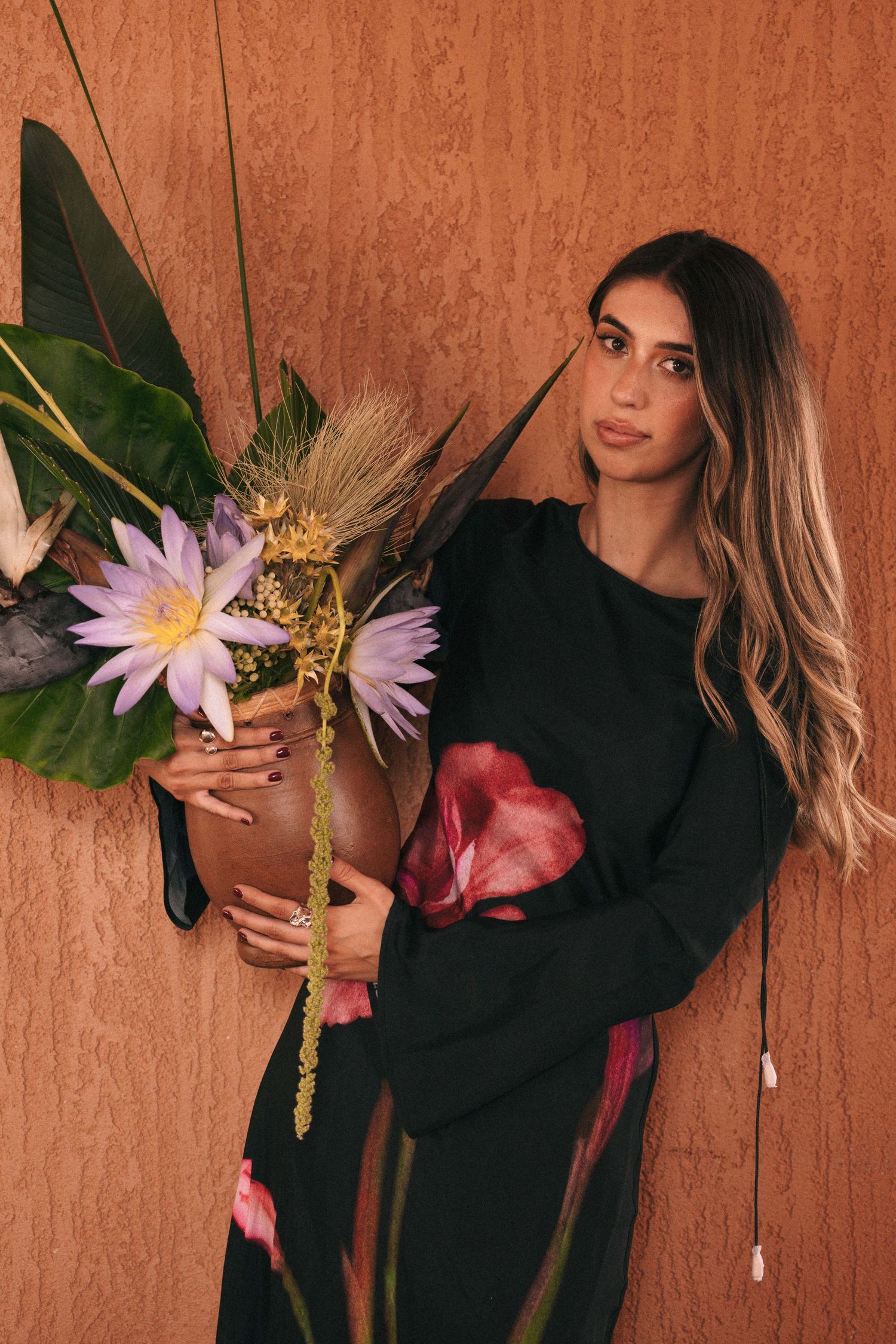Branding Photography Sessions capture an entrepreneur in a black floral dress holding a tropical flower arrangement.