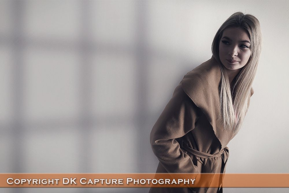 Fashion portrait with window shadow patterns and soft, natural lighting.