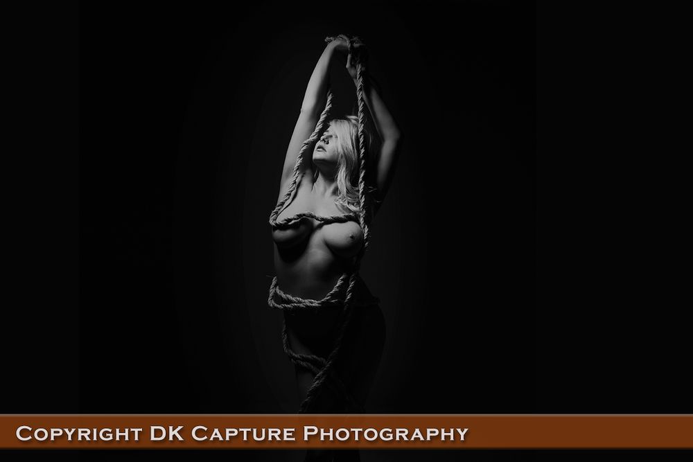 Artistic black and white photo of a figure stretching upward in dark atmospheric lighting.
