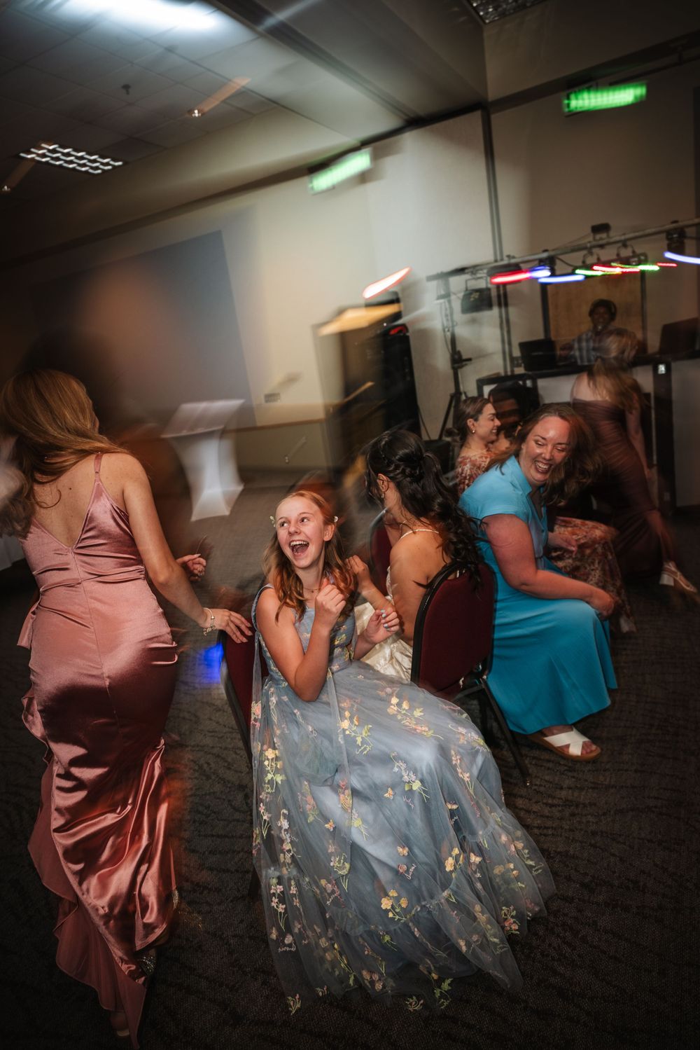Joyful celebration with dancers in formal dresses enjoying a wedding reception party.