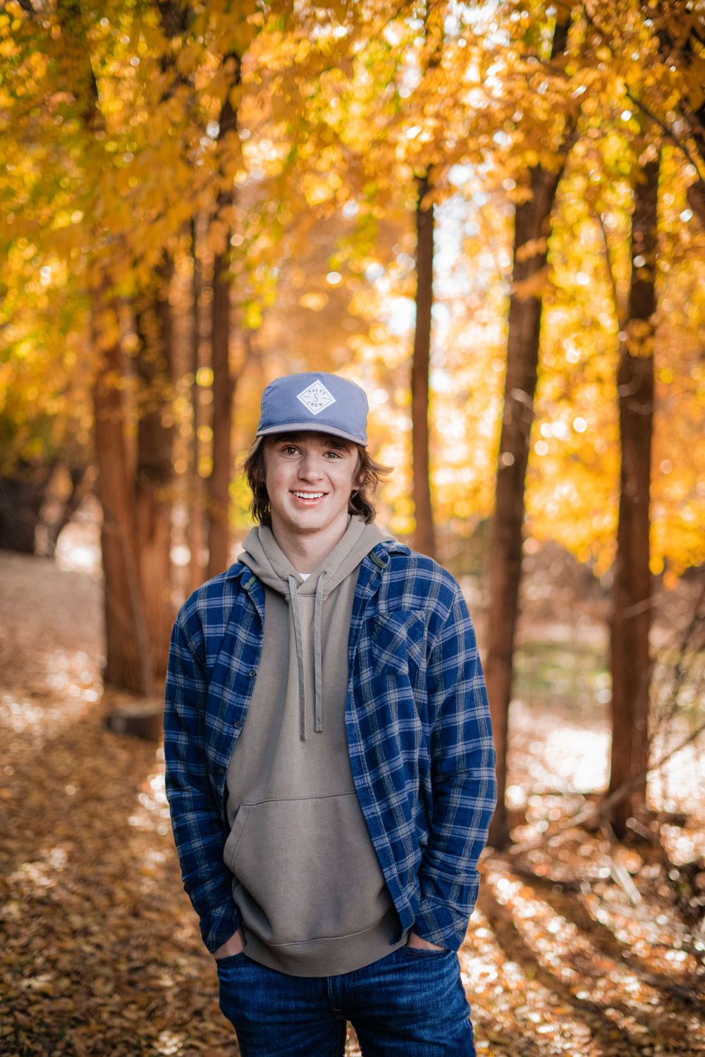 Autumn forest scene with golden leaves and figure in plaid flannel and hoodie.