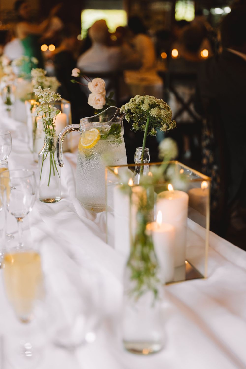 Wedding table decorated with delicate floral arrangements, candles and crystal glasses.