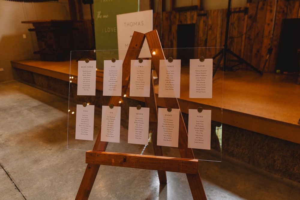 Wooden easel displays wedding seating chart cards against rustic background.
