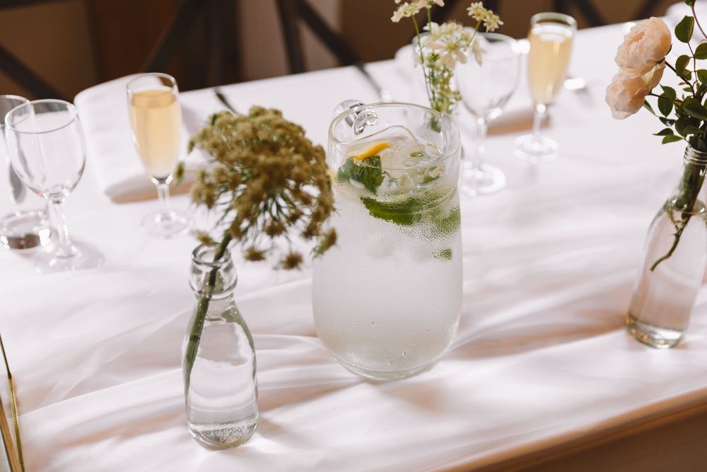Simple wedding table centerpieces with wildflowers in glass vases and lemon water.