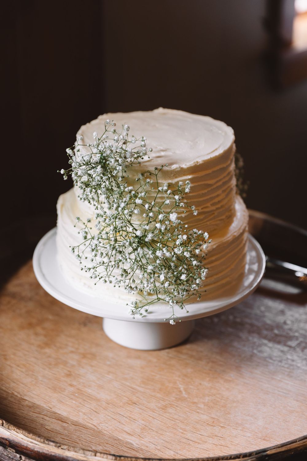 A simple white two-tier wedding cake decorated with delicate baby's breath flowers.