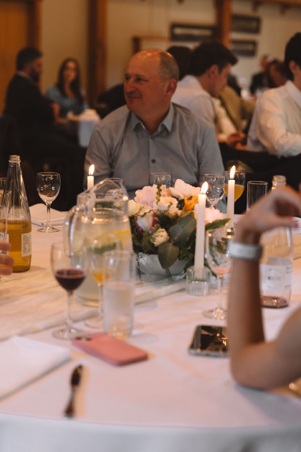 An intimate dinner table setting with wine glasses, candles and floral centerpieces.