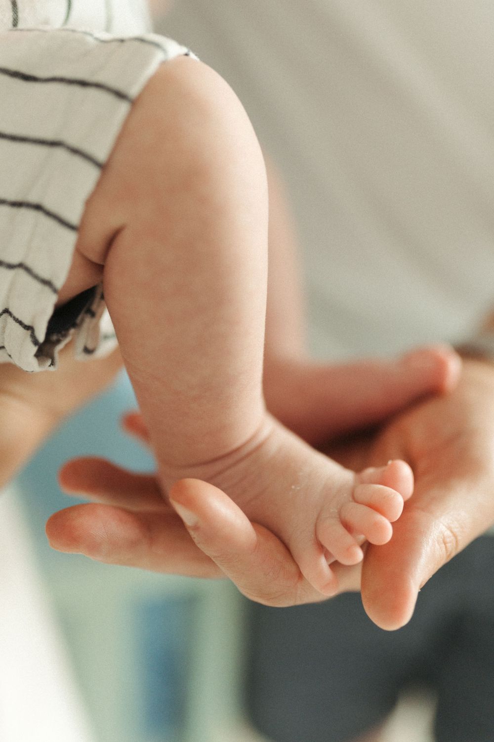 Close-up of a tiny baby foot being gently held in an adult's hand showing tender skin and small toes.