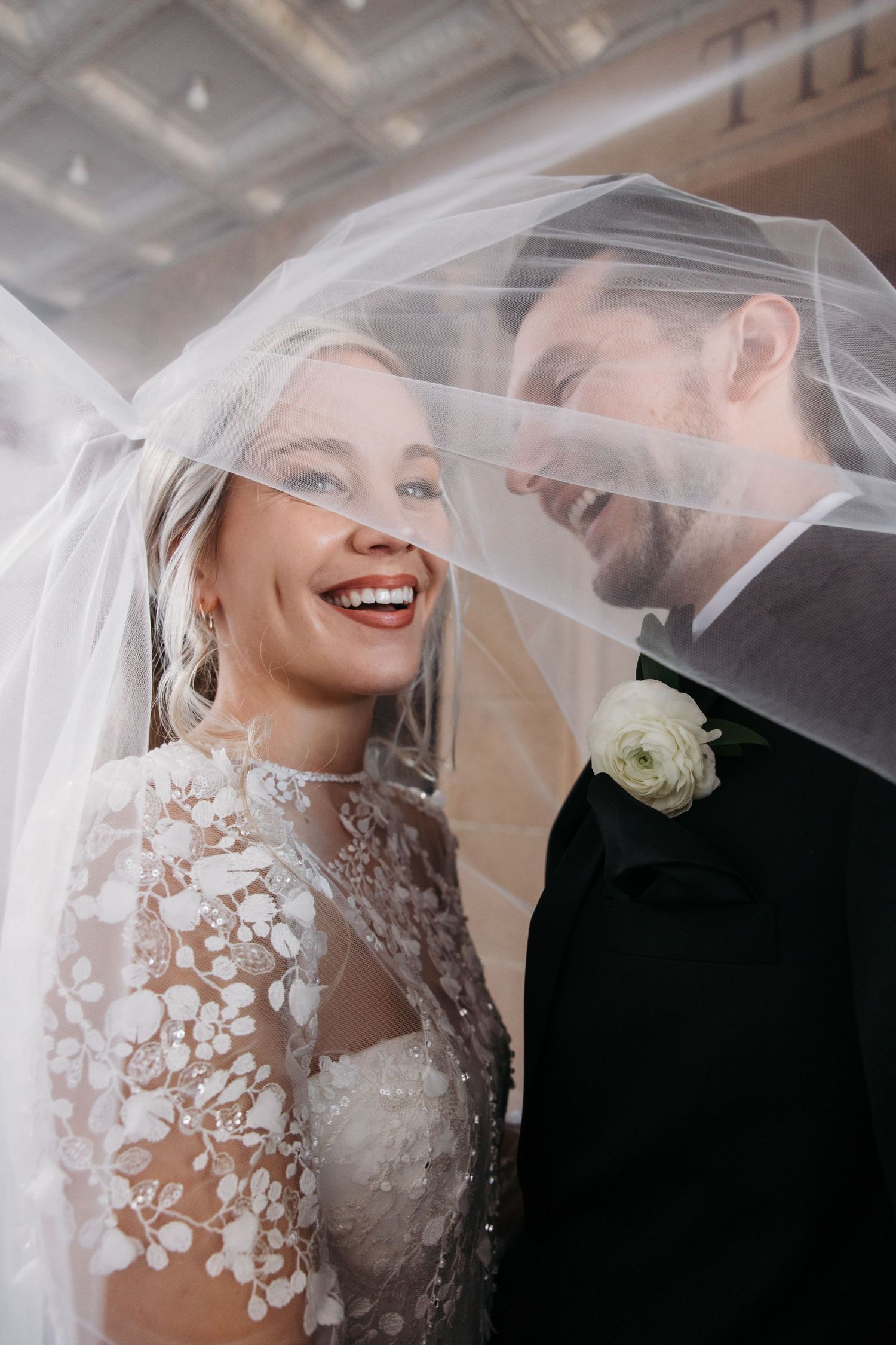 An intimate moment shared under a delicate lace veil during a wedding ceremony.