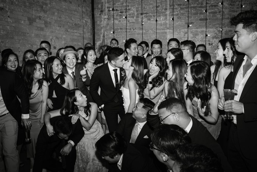 Group photo, bride and groom kissing at reception at The loft distillery district, by Toronto Wedding Photographer Jess GC Photography