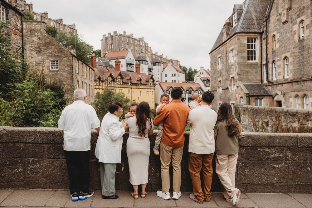 A group of people overlook a scenic view from a stone bridge in Edinburgh's historic Old Town on a cloudy day.
