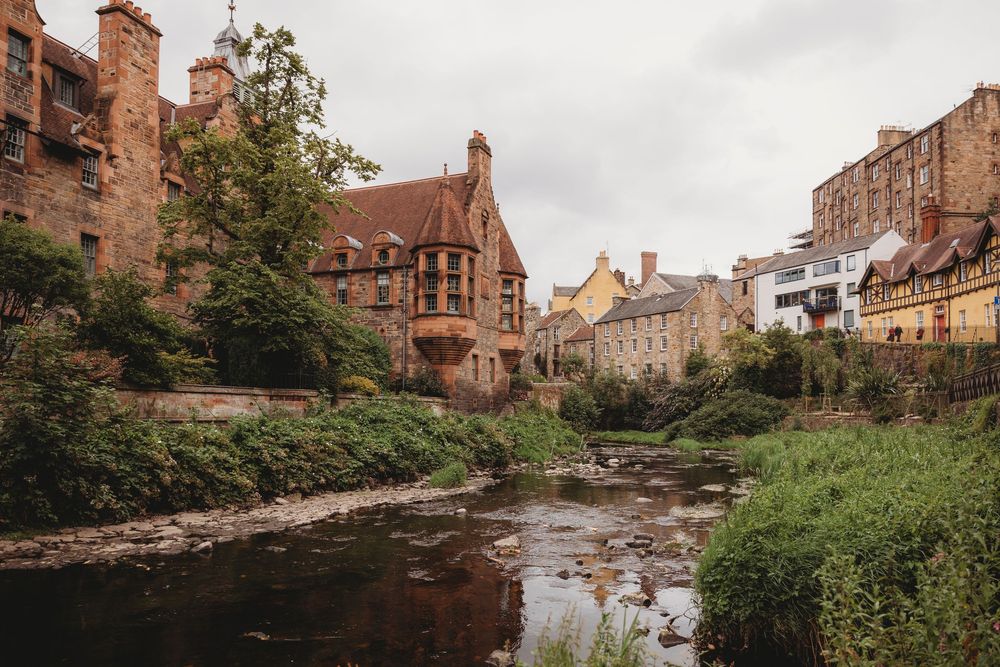 Historic Dean Village with Water of Leith river flowing past traditional Scottish stone buildings in Edinburgh, Scotland.