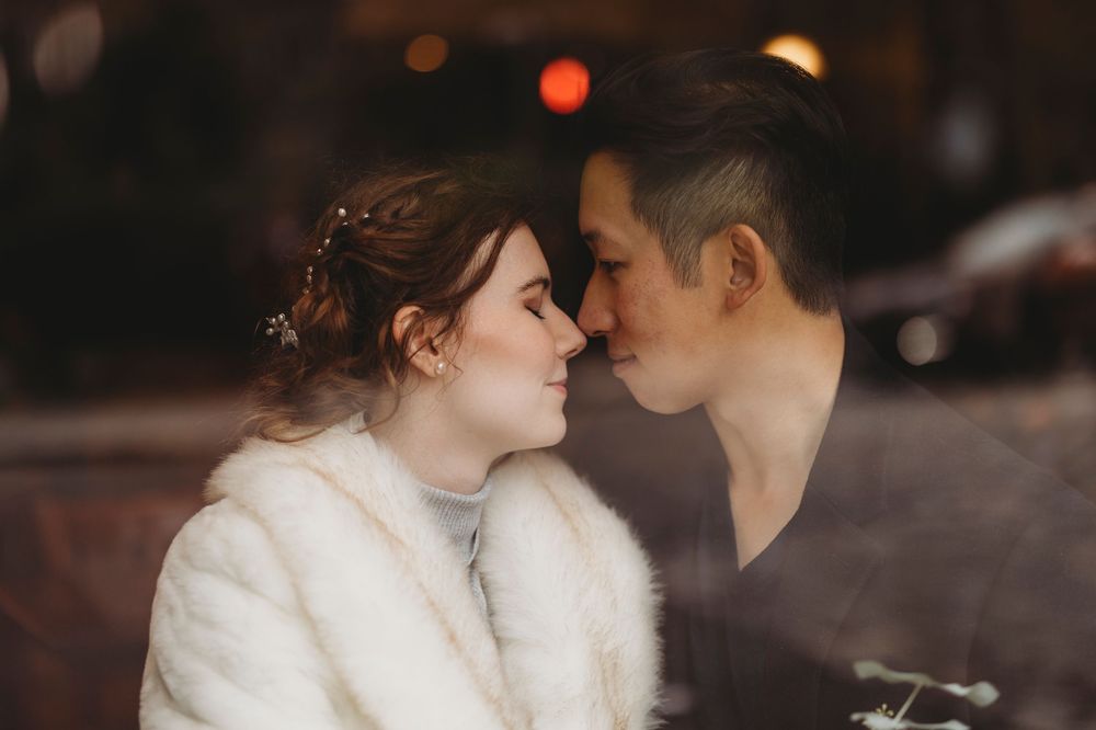 Romantic couple sharing an intimate moment together against a blurred bokeh background in winter attire.