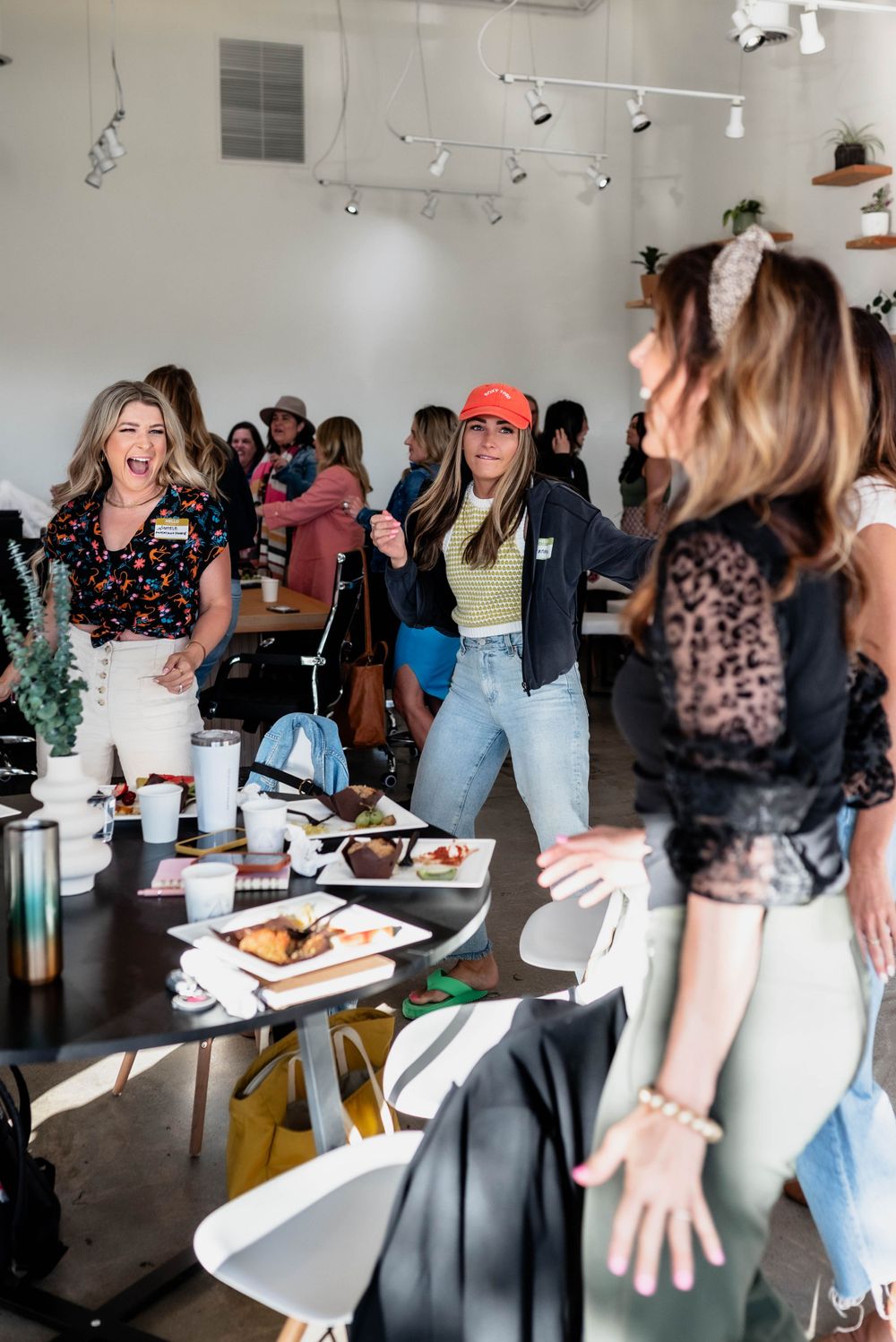 Lively social gathering with people enjoying food and drinks in bright modern space.