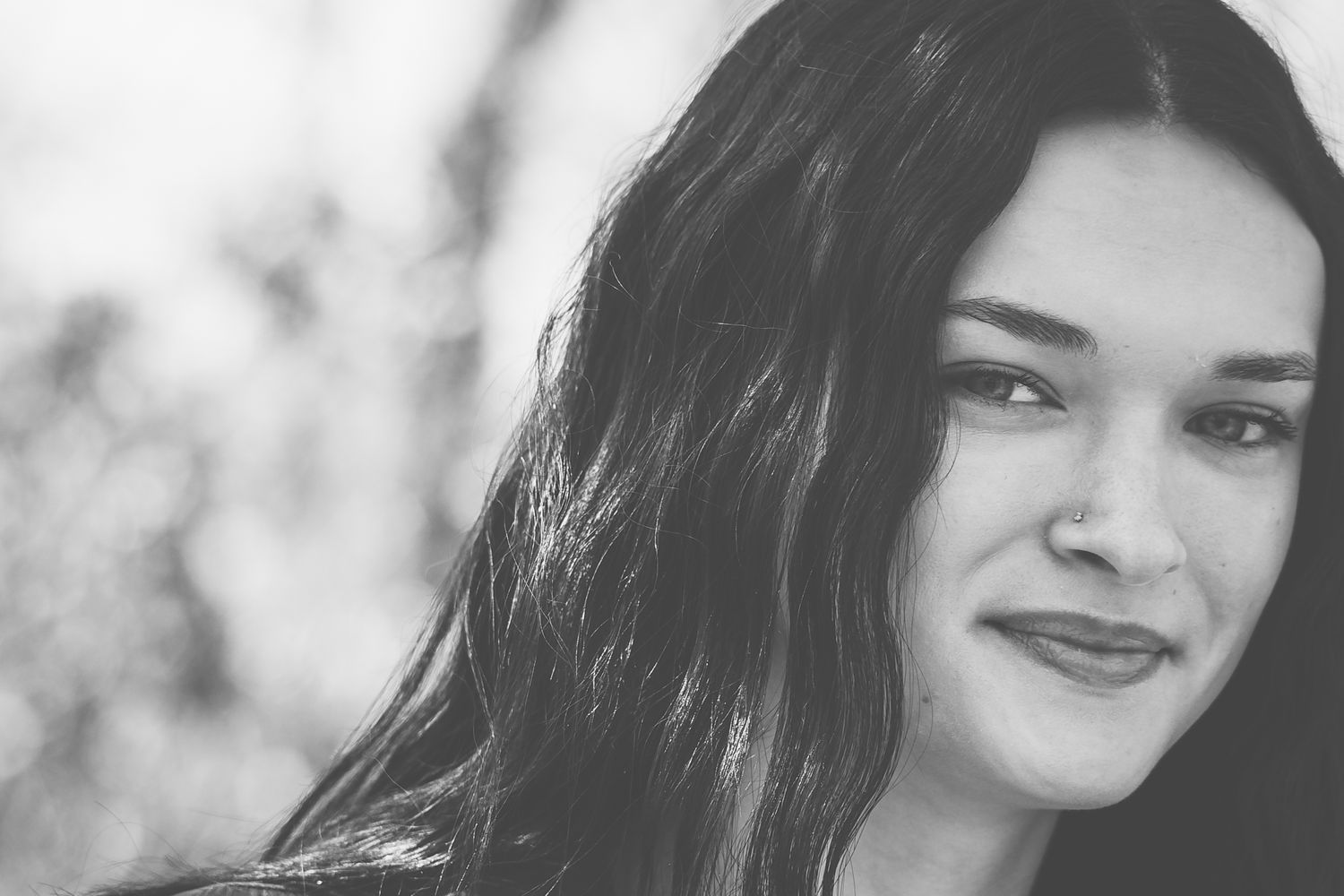 A black and white portrait showing a gentle smile and long dark hair.