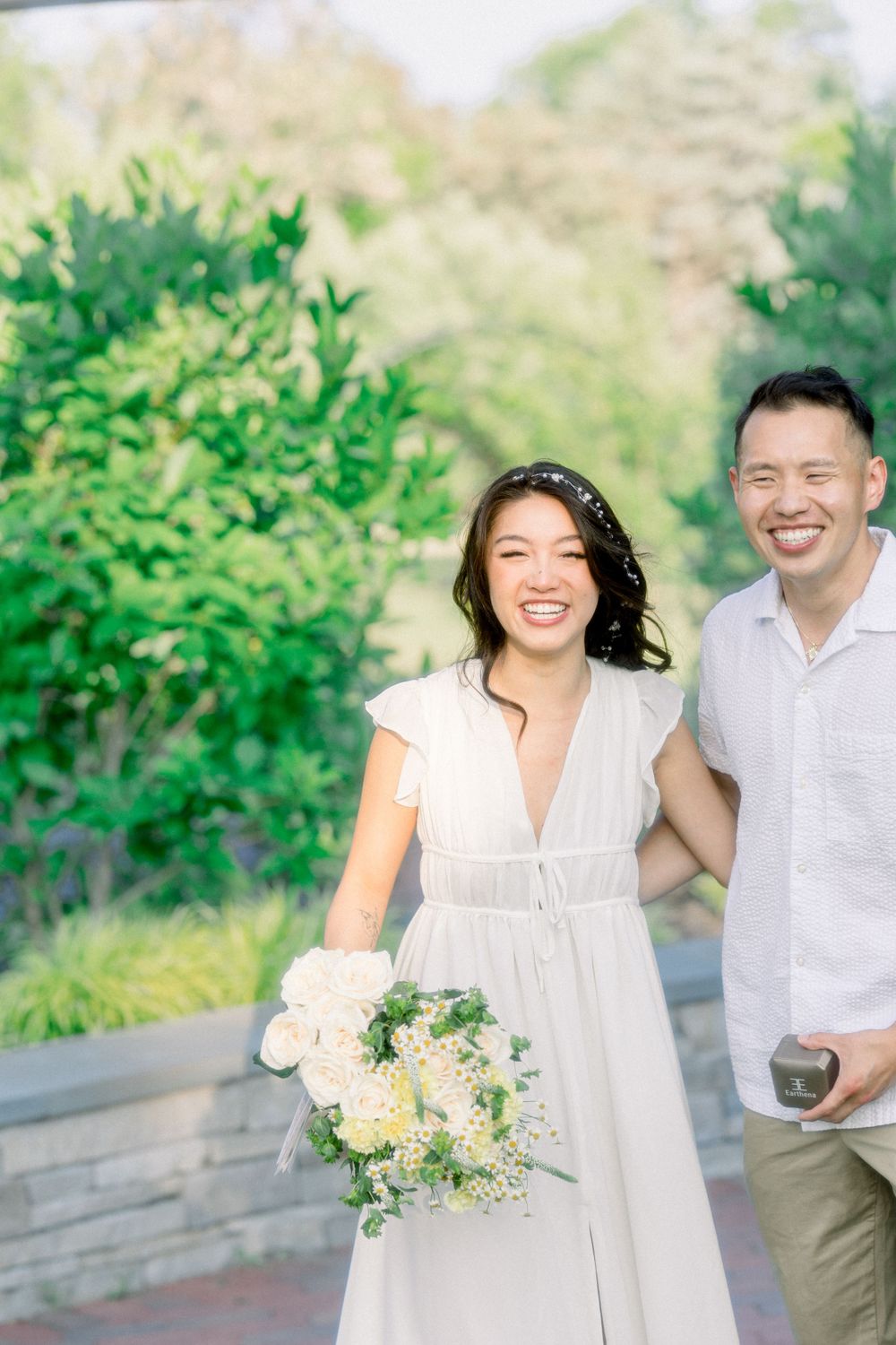 A couple shares a happy moment together on a garden path with white flowers.