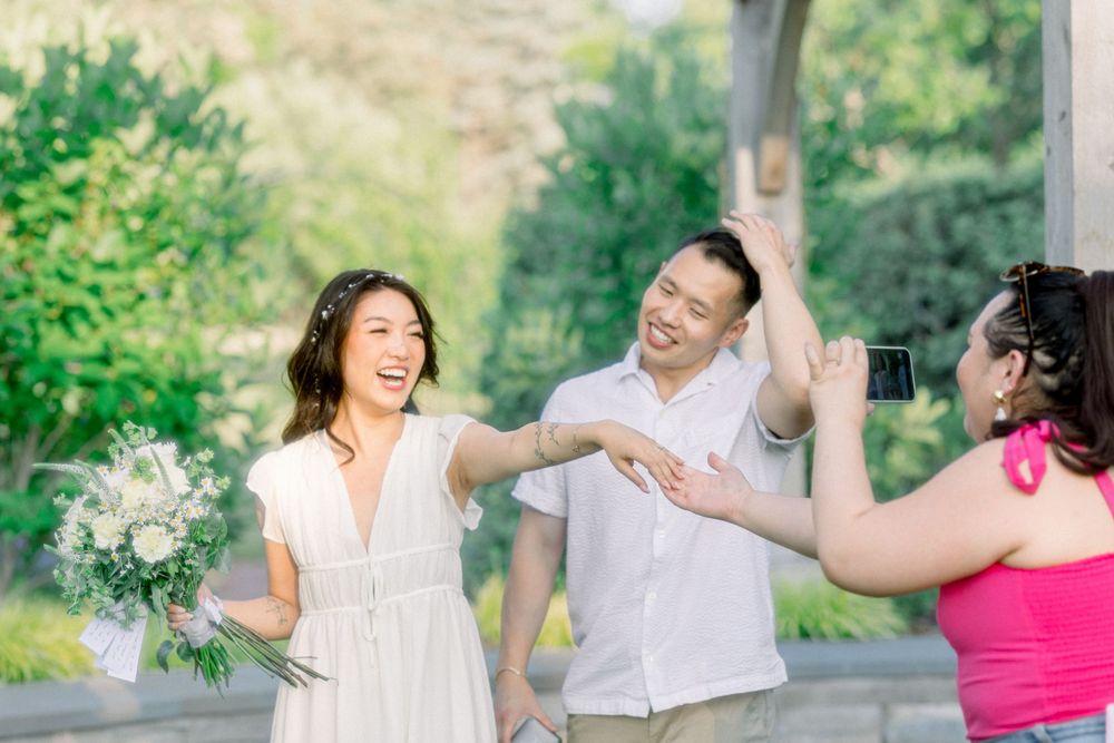 Three people share an enthusiastic celebration moment in a sunny garden setting.