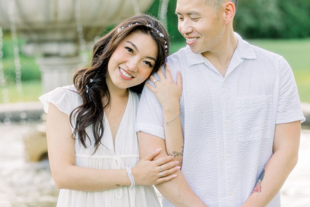 A romantic couple shares a tender moment outdoors in white summer attire.