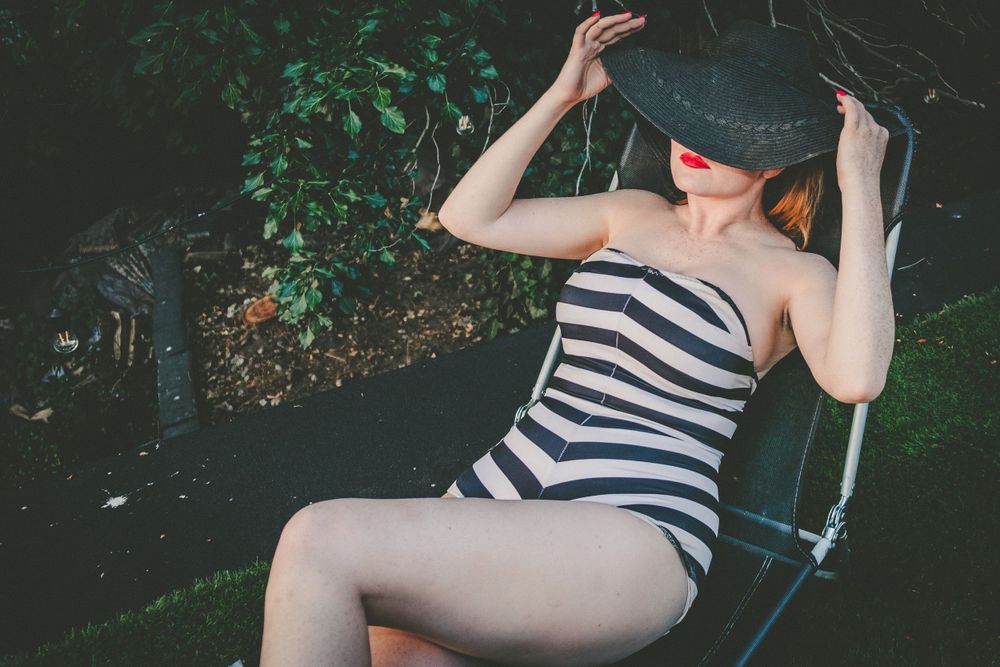 Playful summer portrait in striped swimsuit on outdoor swing.